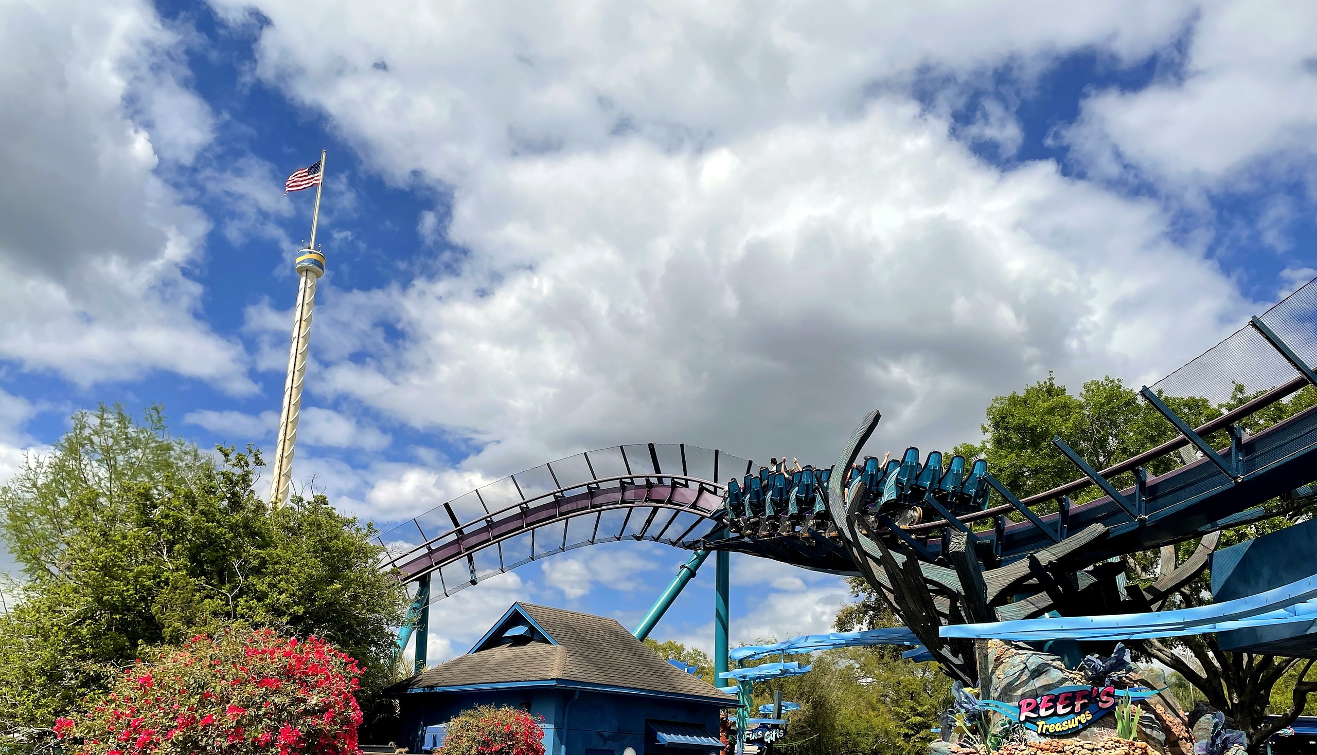 A Mako train on the track above the midway near the entrance with the Sky Tower behind at SeaWorld Orlando, March 2021