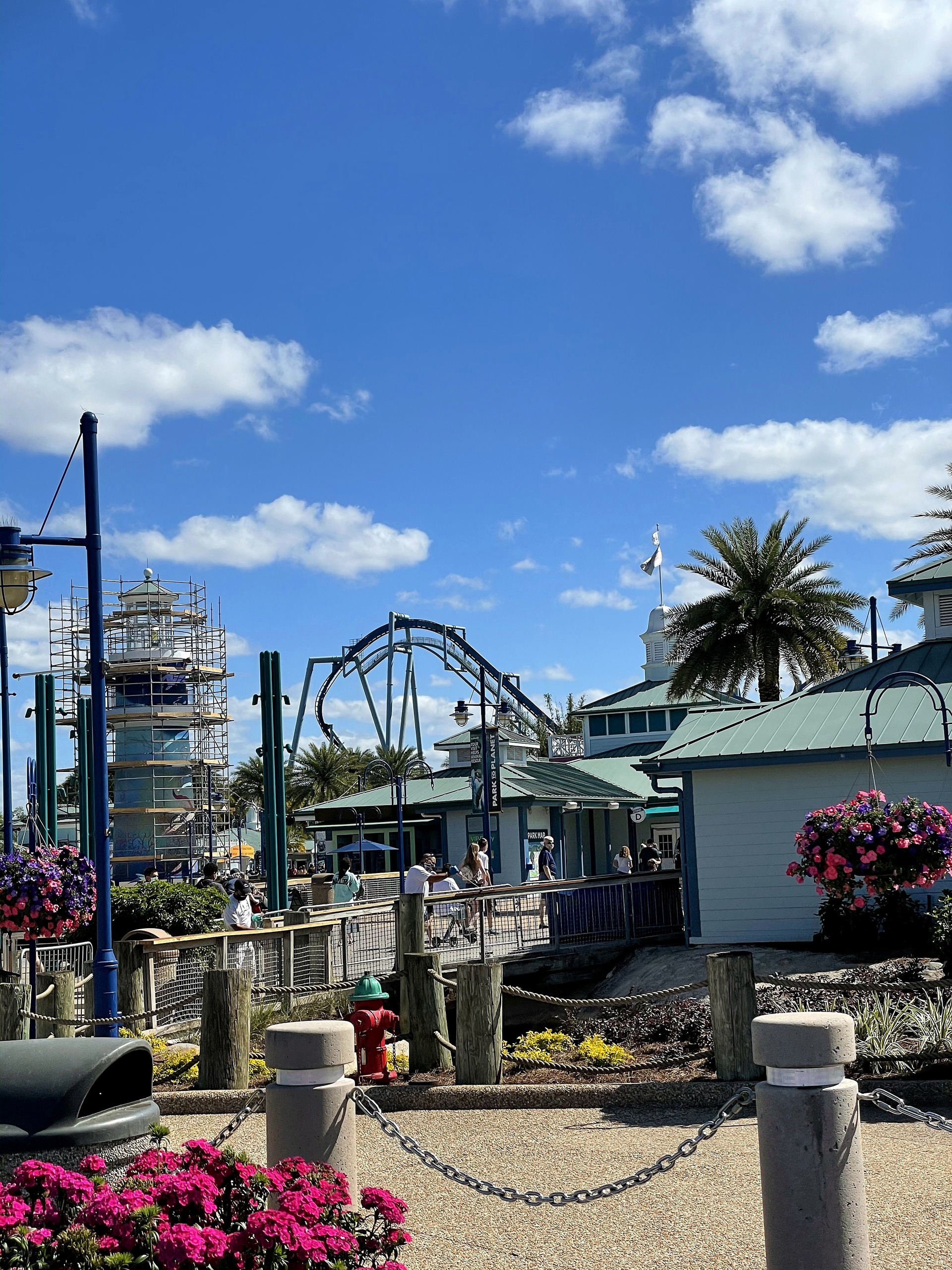 Manta's loop above the rooftops of the entrance plaza with a lighthouse under scaffolding at left at SeaWorld Orlando, March 2021