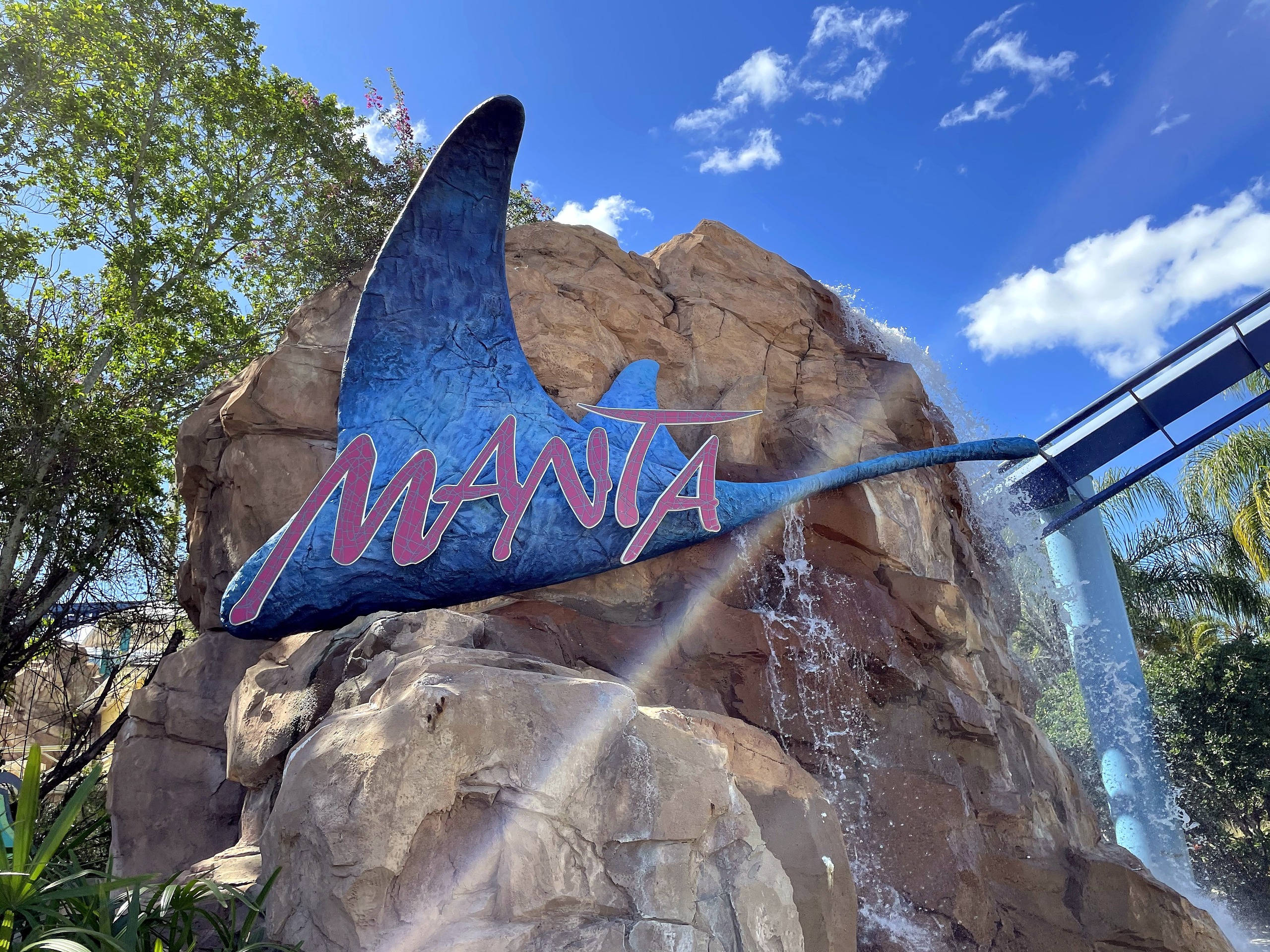 The Manta sign on the rockwork waterfall with the track curving past at right at SeaWorld Orlando, March 2021