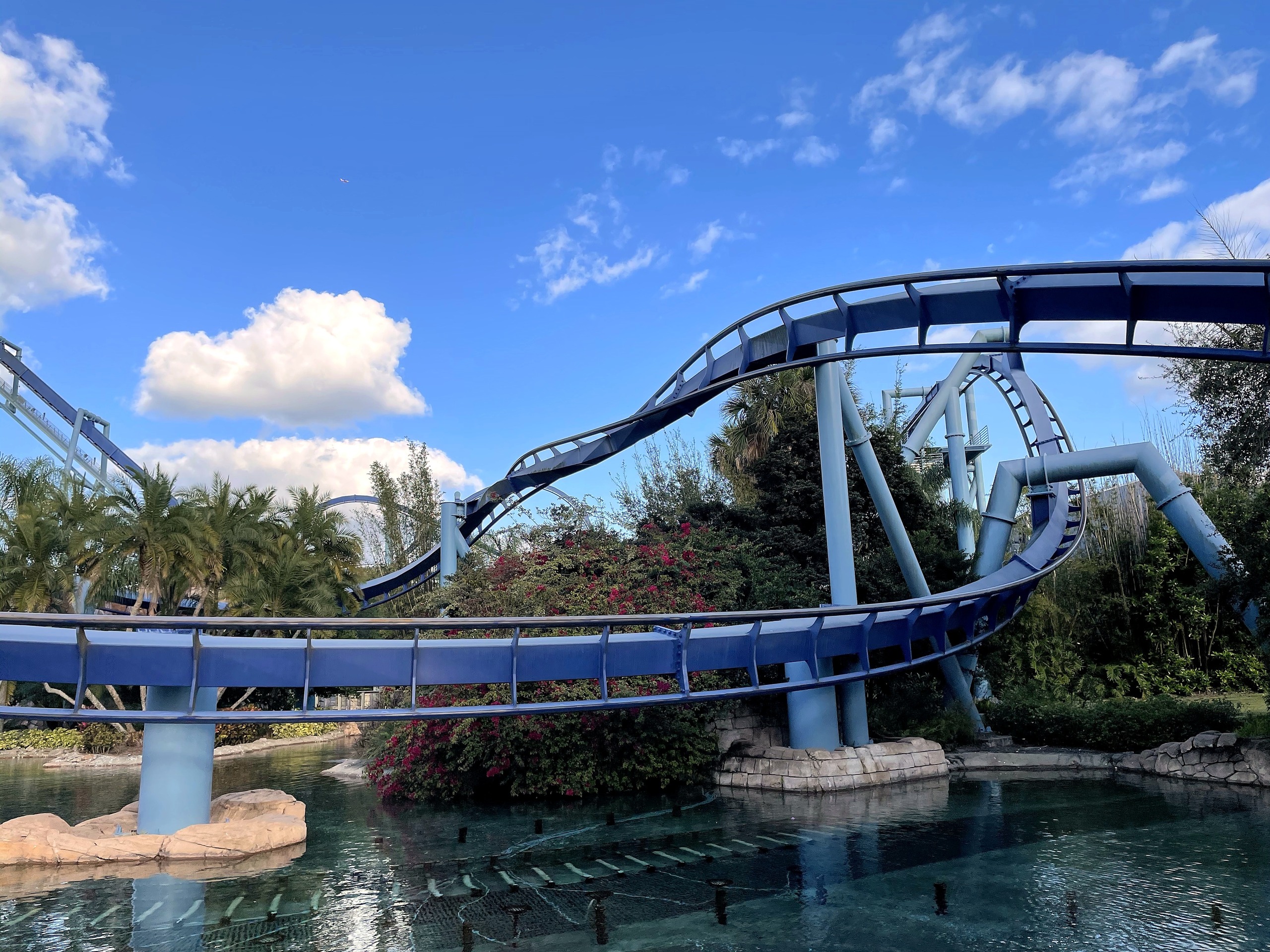 Manta's blue track curving over the lagoon on its support columns in the late afternoon at SeaWorld Orlando, March 2021
