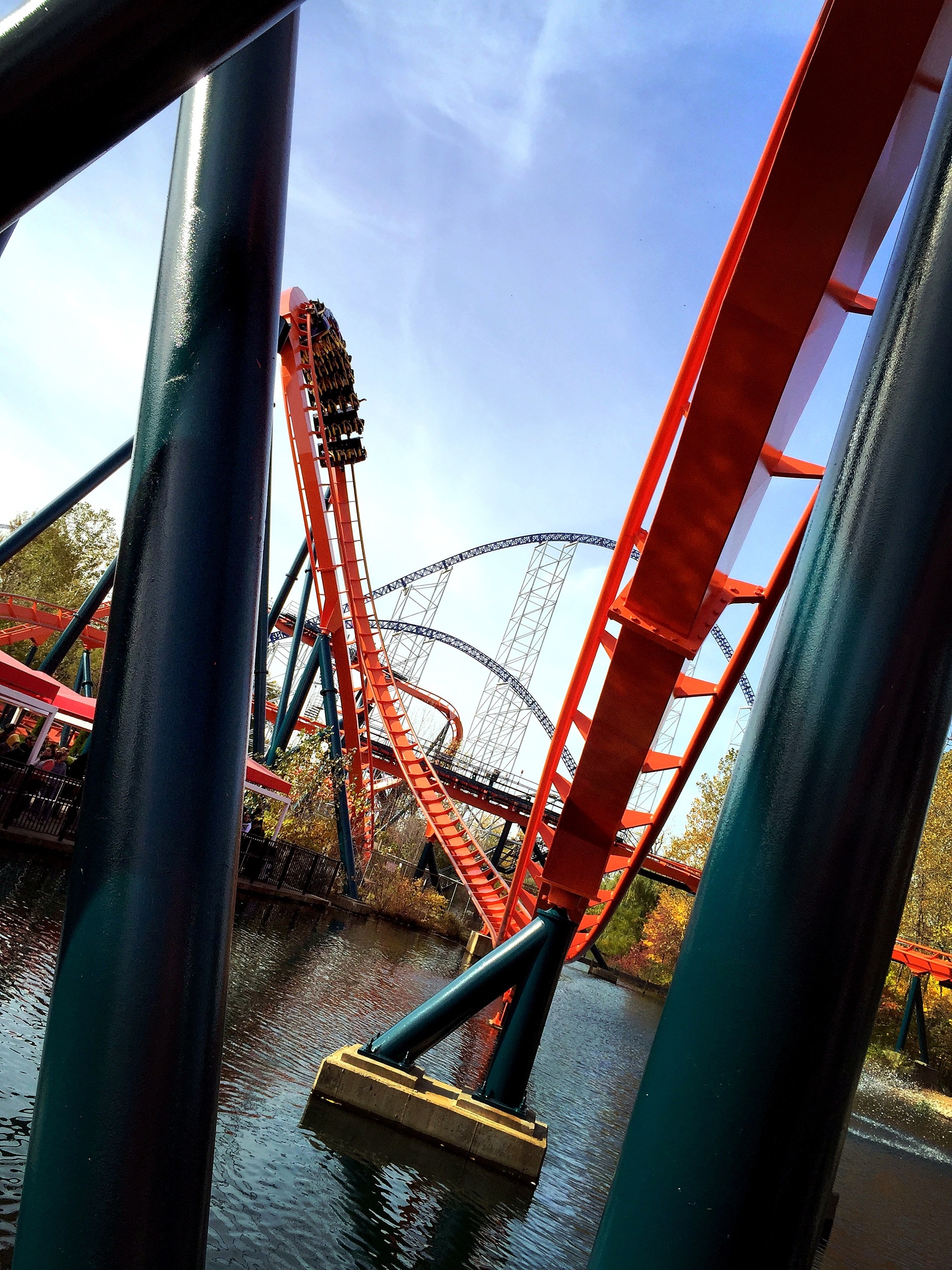A Mantis train at the top of the loop in Rougarou's orange and teal, framed by supports over the lagoon at Cedar Point, October 2014