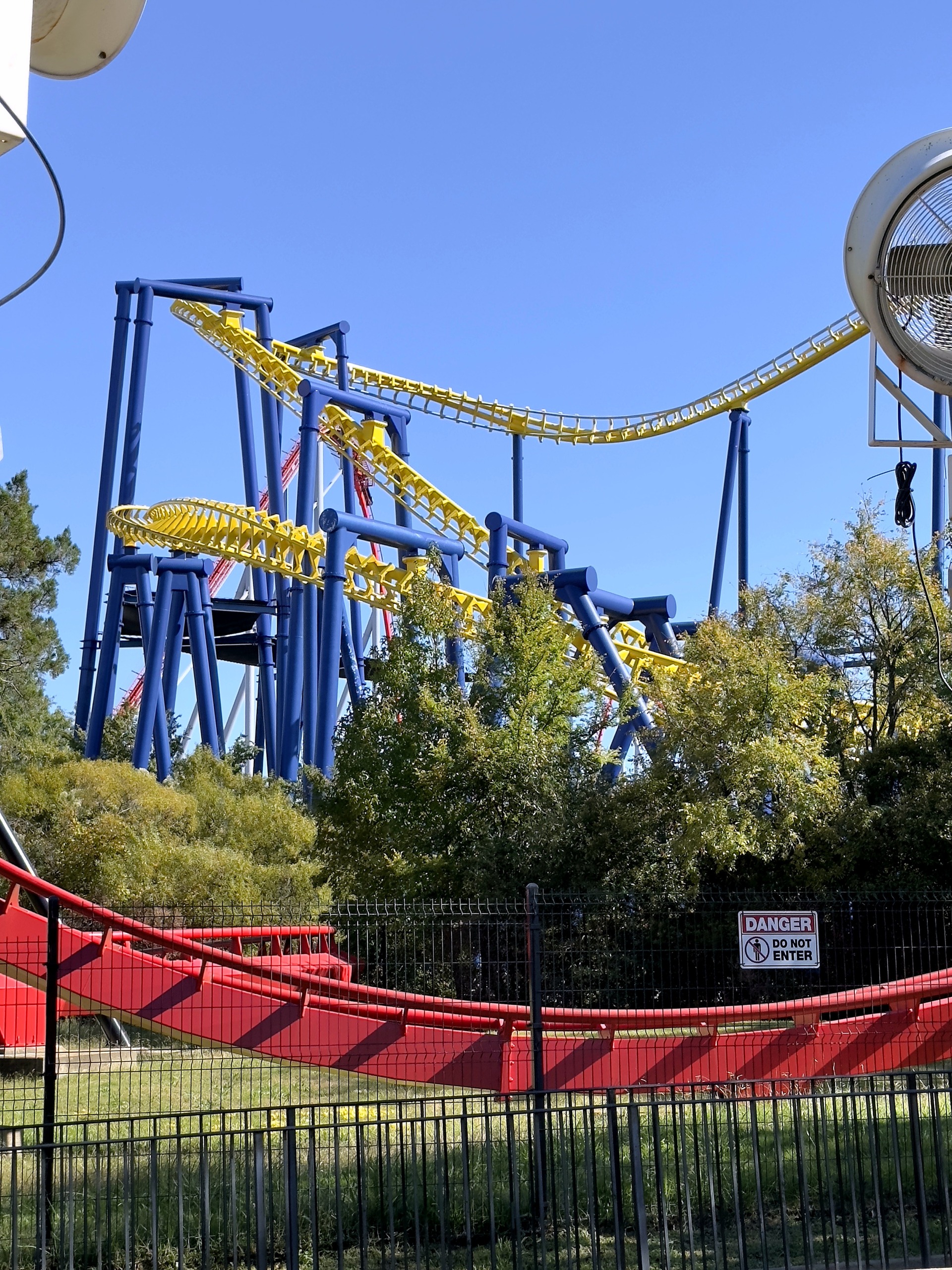 Nighthawk's yellow track and blue supports above a red coaster track at Carowinds, October 2024