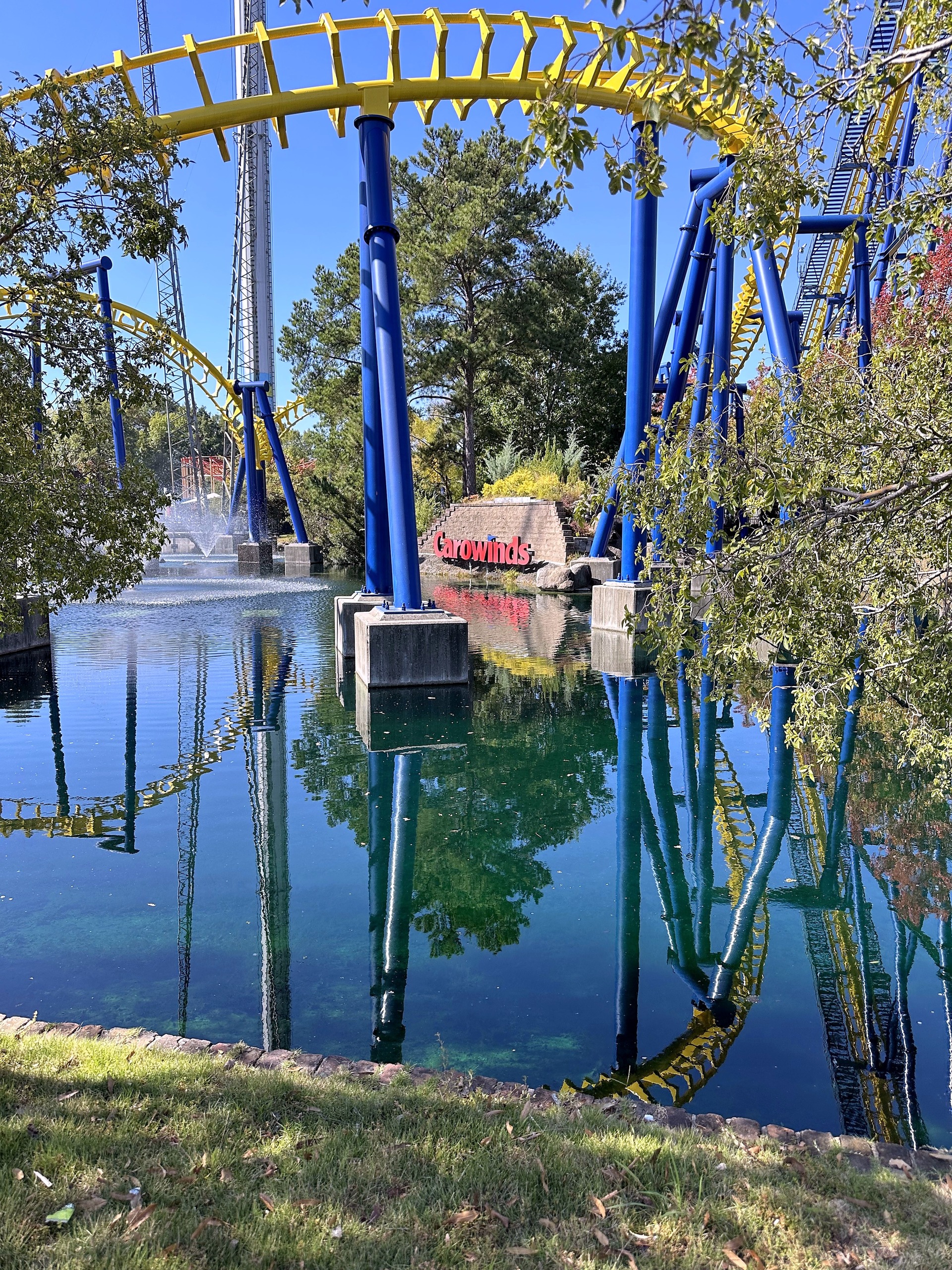 Nighthawk's yellow track over the pond with the Carowinds sign and fountain at Carowinds, October 2024
