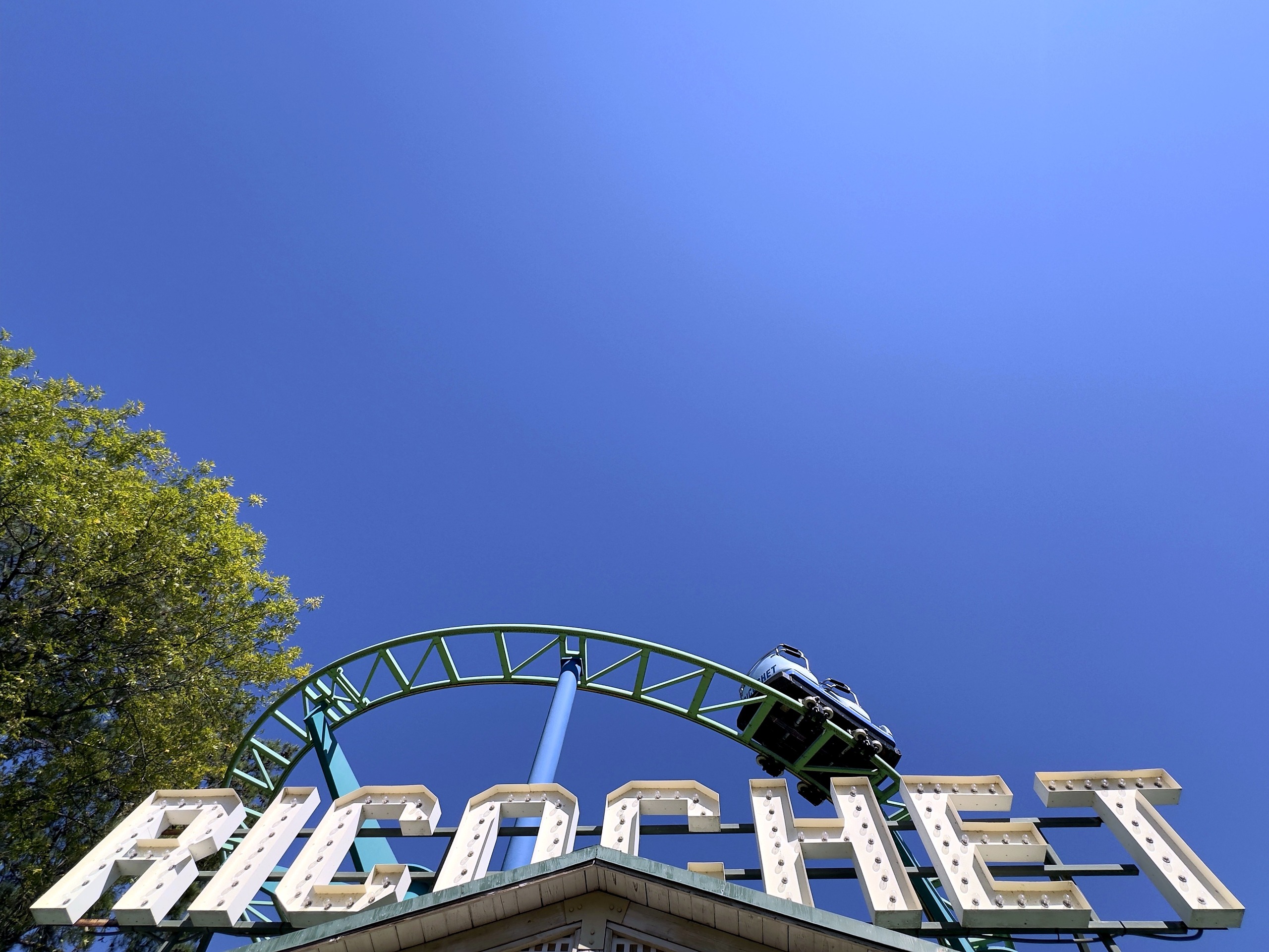 A Ricochet car on the hairpin above the marquee letters at Carowinds, October 2024