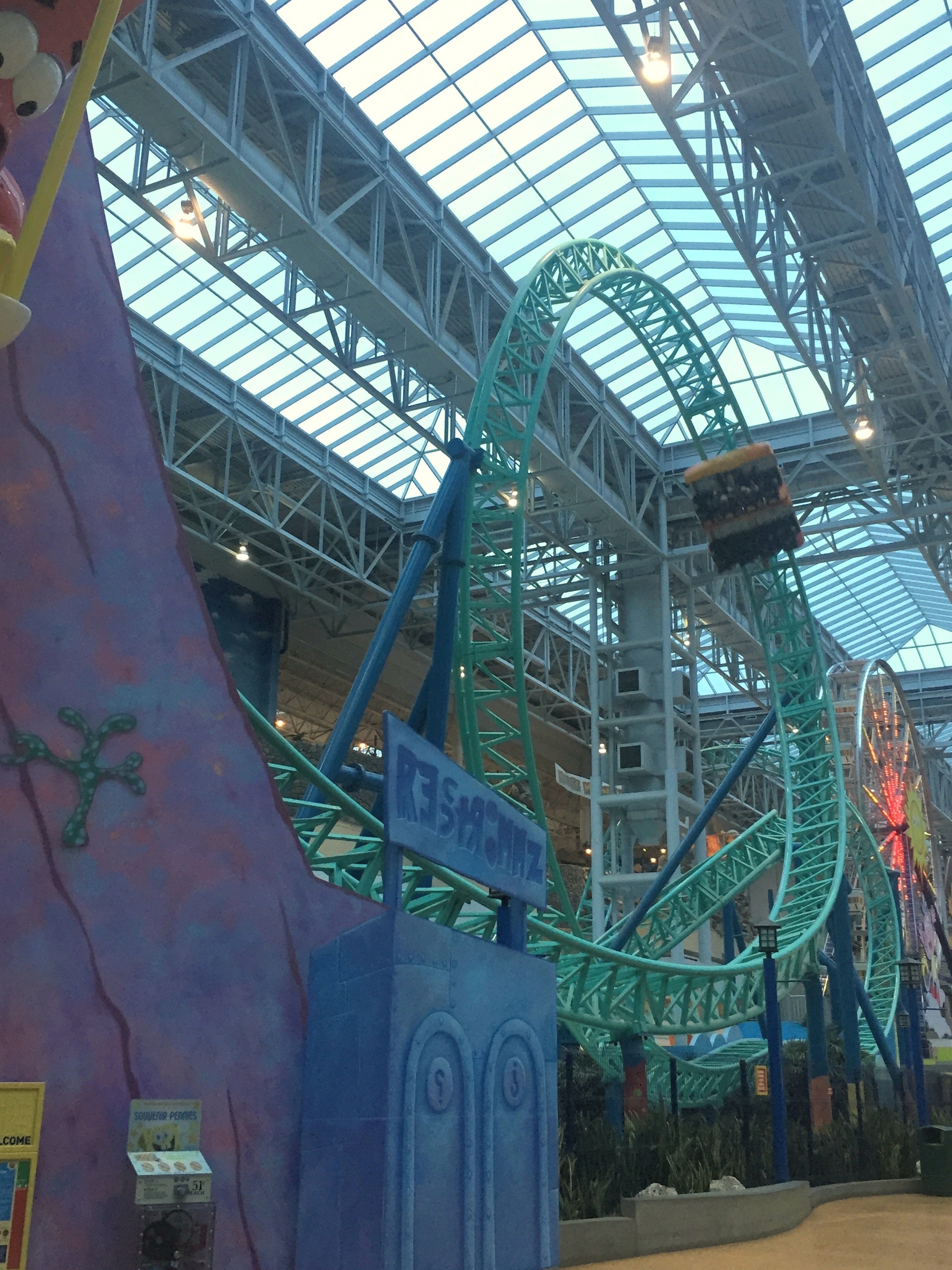 A SpongeBob SquarePants Rock Bottom Plunge train on the teal loops beyond the purple rockwork at Nickelodeon Universe, November 2015