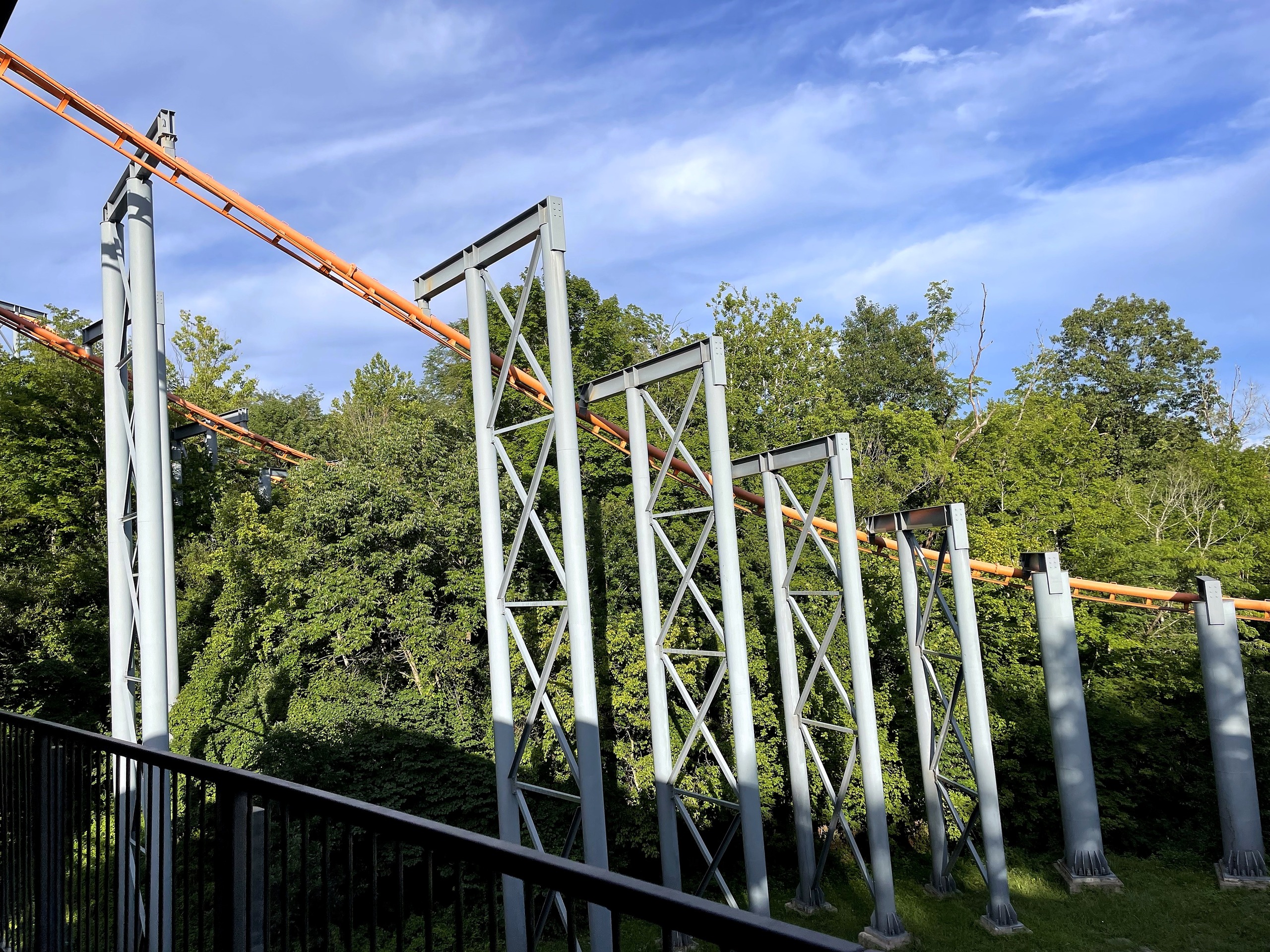 The Bat's orange track swinging over a row of gray supports, Kings Island, July 2022