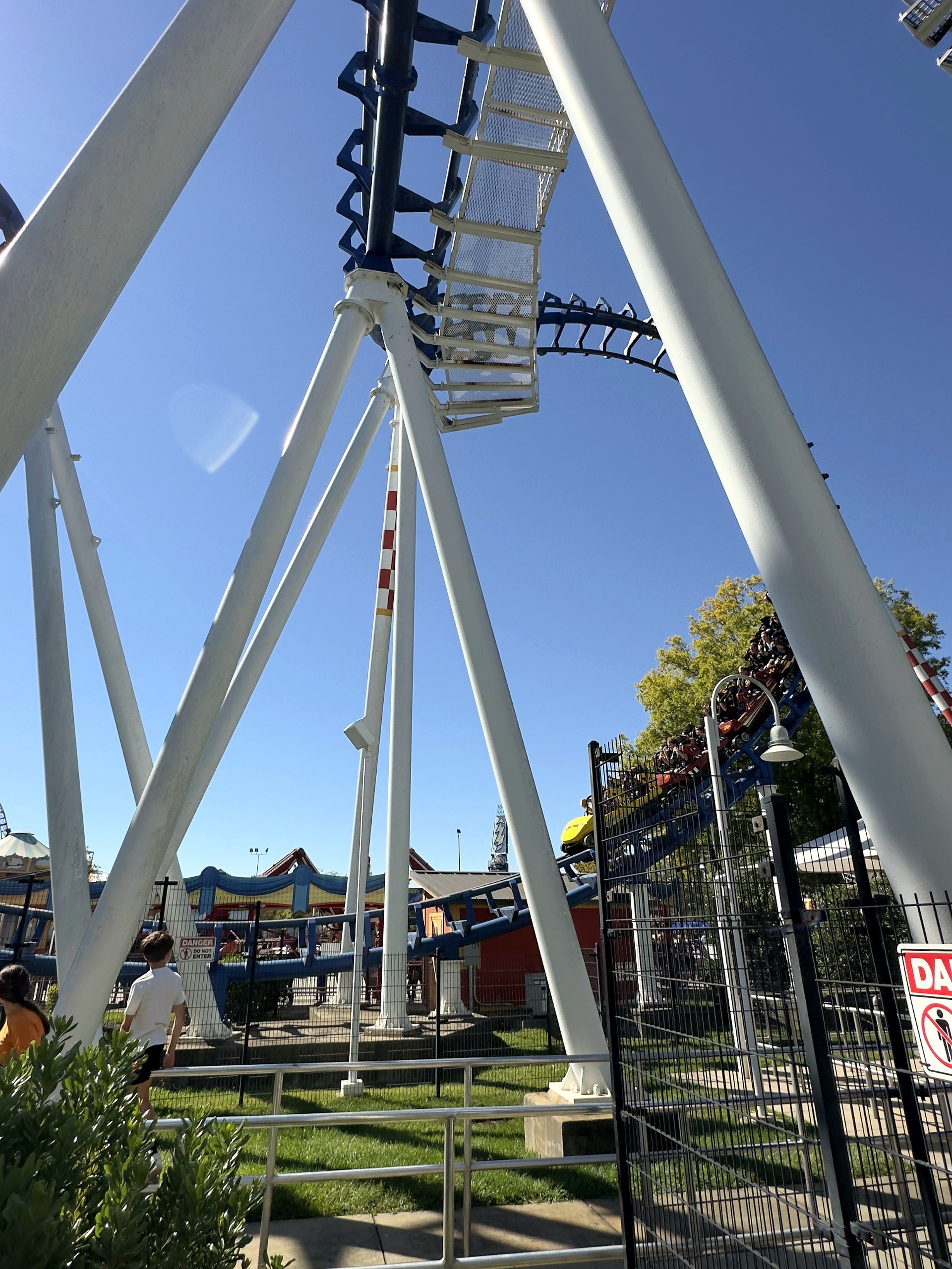 A Flying Cobras train passing the white supports beside the queue at Carowinds, October 2024