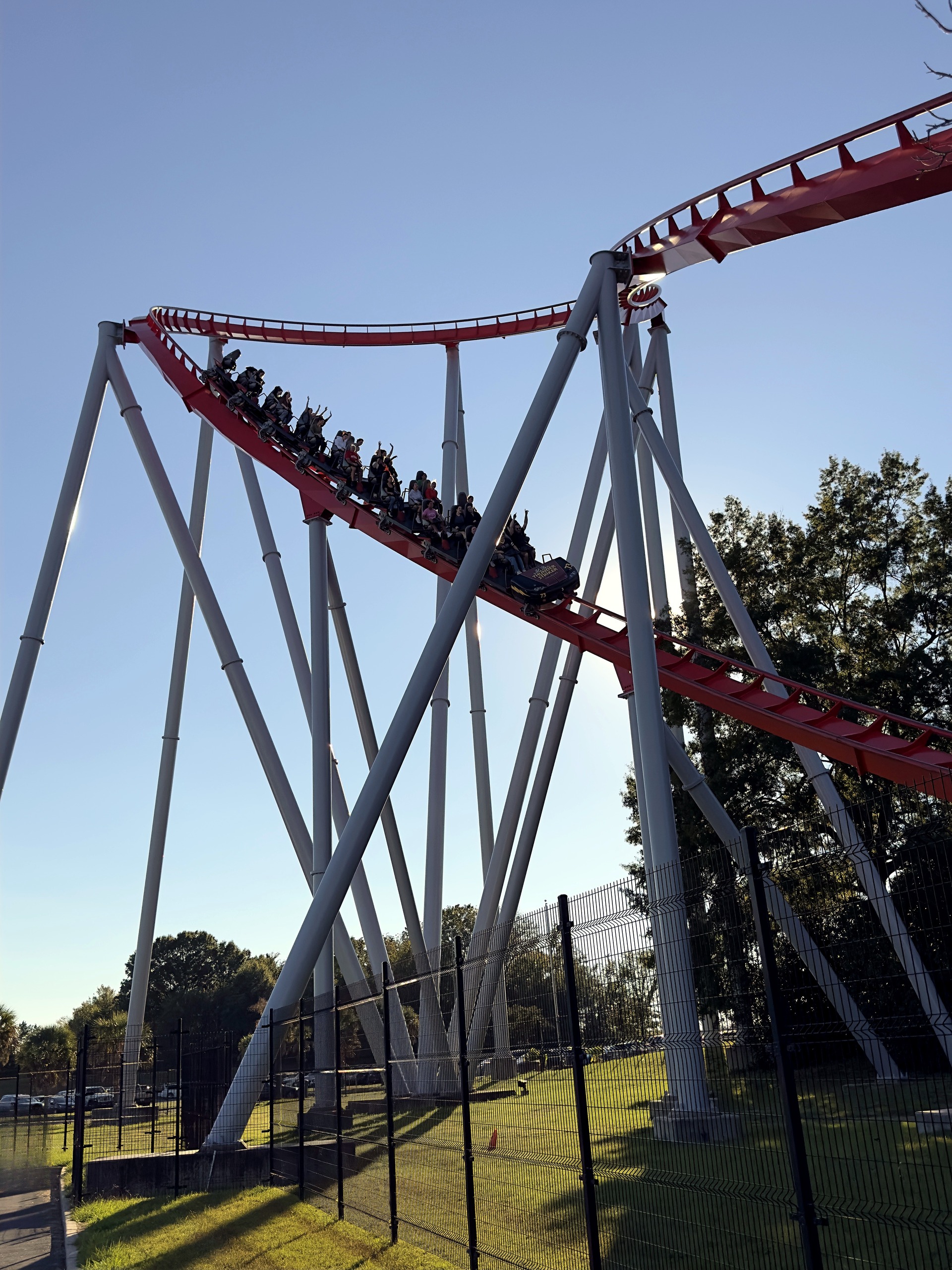 A Thunder Striker train with riders' hands up on a red hill at Carowinds, October 2024