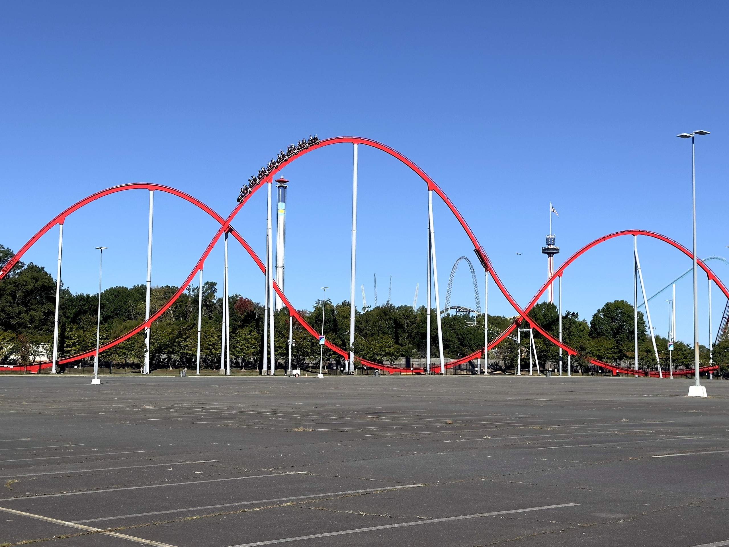 A Thunder Striker train cresting a camelback hill above the parking lot at Carowinds, October 2024