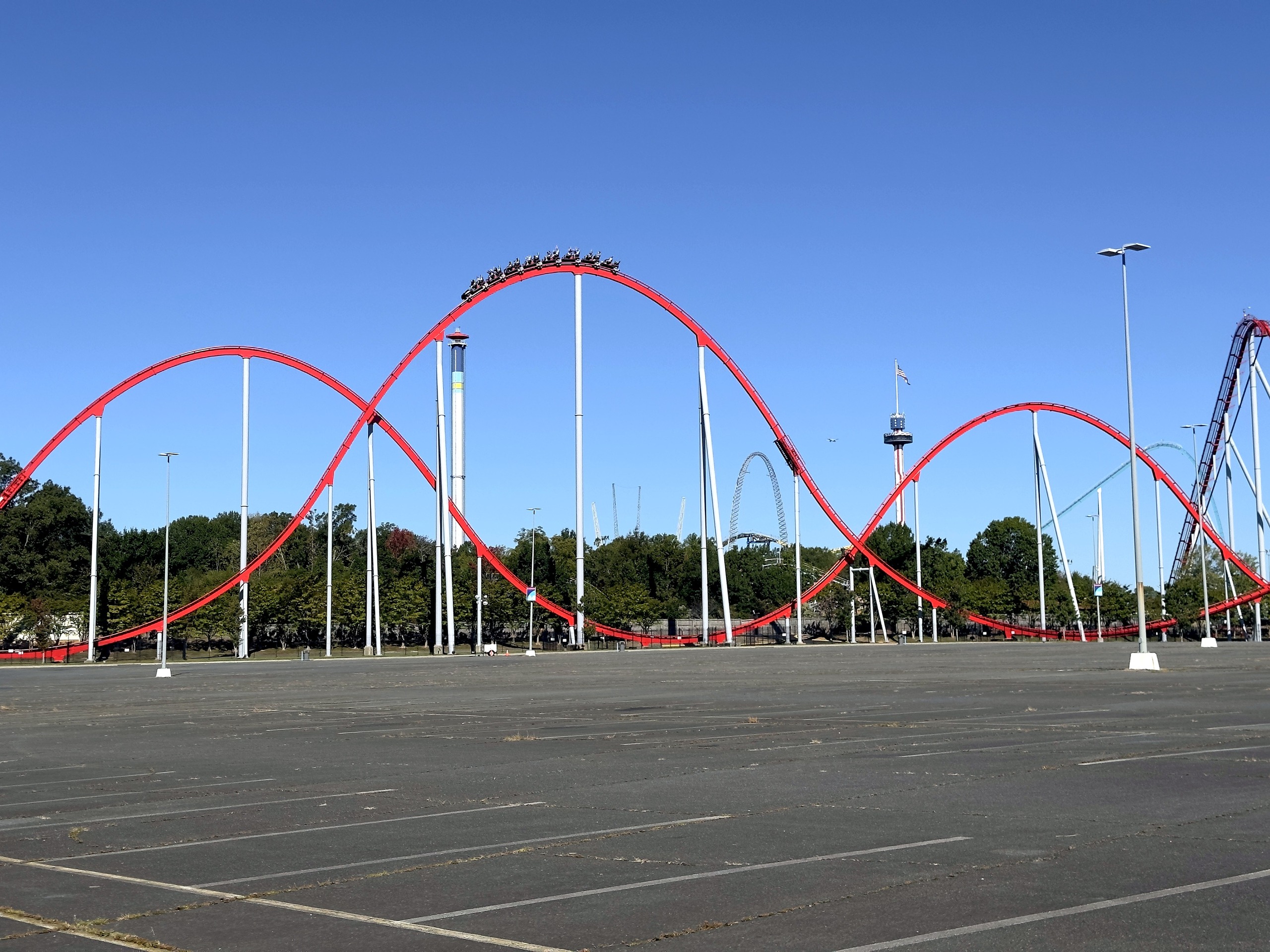 A Thunder Striker train cresting a red airtime hill above the parking lot at Carowinds, October 2024