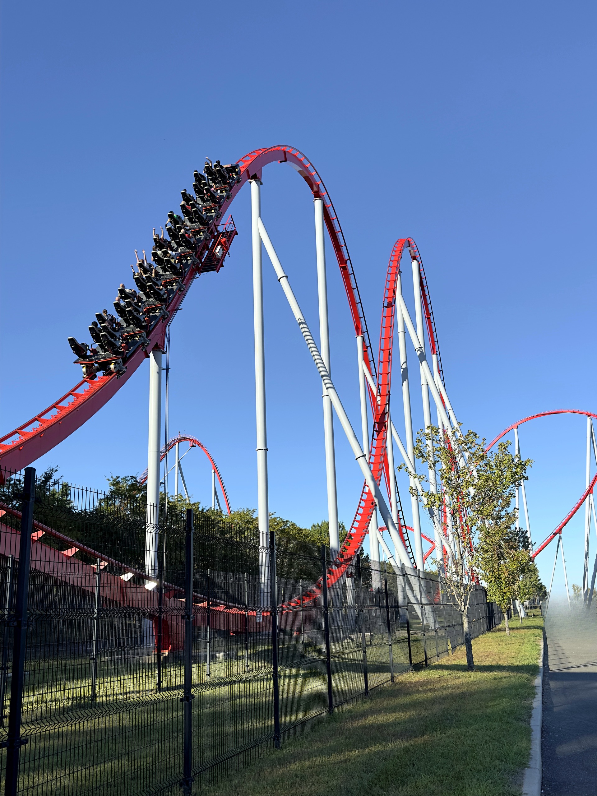 A Thunder Striker train climbing a red hill with more hills beyond at Carowinds, October 2024