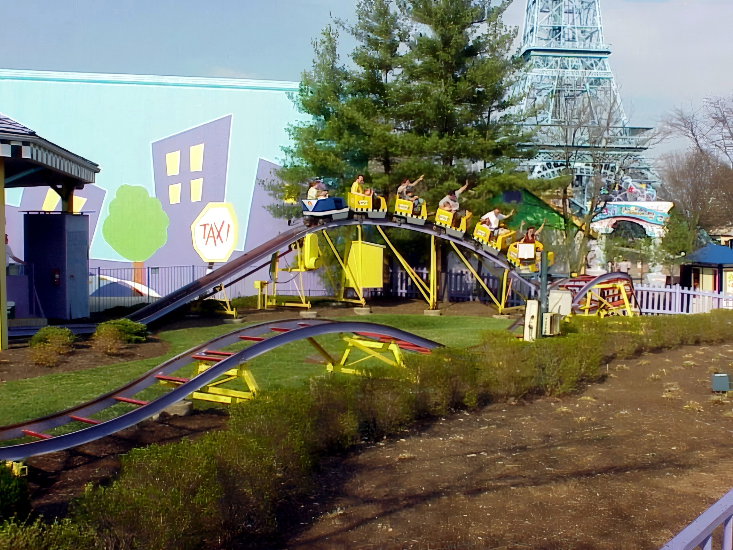 A Top Cat's Taxi Jam train full of riders on the curve beside the Taxi sign, the Eiffel Tower behind, at Paramount's Kings Island, April 2001