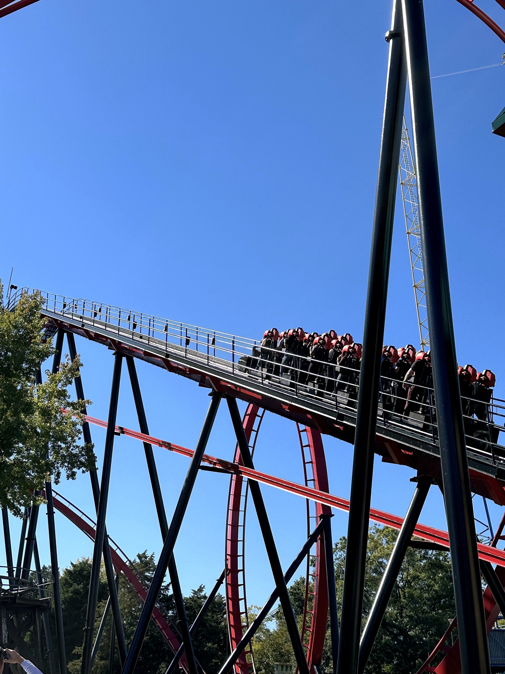 A Vortex train climbing the lift hill with its riders standing at Carowinds, October 2024