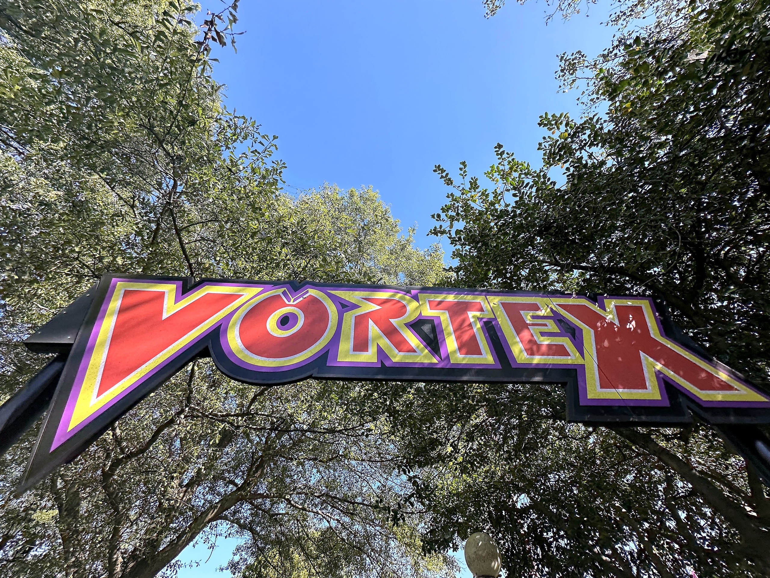 The Vortex entrance sign framed by trees at Carowinds, October 2024